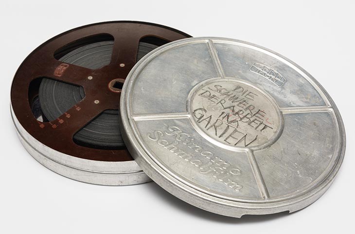 ein Film aufgerollt liegend in einer geöffneten Filmdose aus Blech