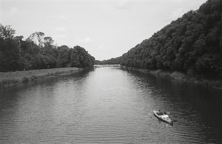 ein Kanal, darauf ein Kanu, Ufer mit Bäumen daneben