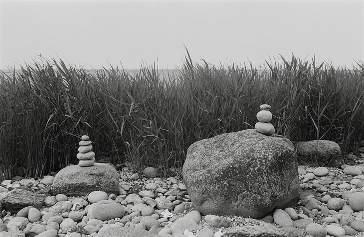 An einem Strand sind Steine zu Pyramiden aufgetürmt.